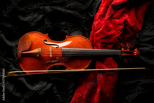 Violin with a bow on black and red drapery background