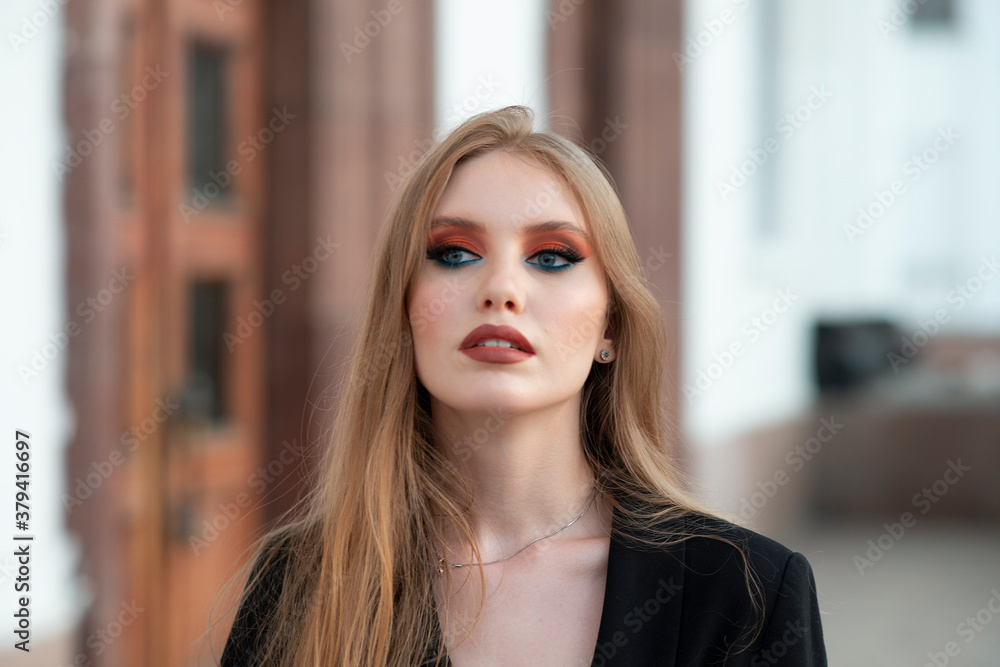 A girl with red hair, dressed in a black jacket, posing against the backdrop of a white building. Looking away. A girl with red hair, dressed in a black jacket, posing against the backdrop of a white building. Looking away.