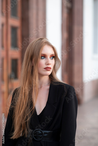 A girl with red hair, dressed in a black jacket, posing against the backdrop of a white building. Looking away. Free Download A girl with red hair, dressed in a black jacket, posing against the backdrop of a white building. Looking away. - GFXLoad