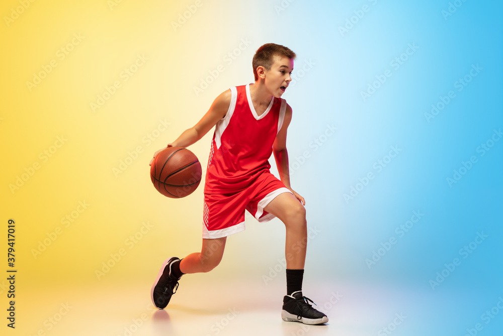 Hurry up. Portrait of young basketball player in uniform on gradient studio background. Teenager confident practicing with ball. Concept of sport, movement, healthy lifestyle, ad, action, motion. Hurry up. Portrait of young basketball player in uniform on gradient studio background. Teenager confident practicing with ball. Concept of sport, movement, healthy lifestyle, ad, action, motion.