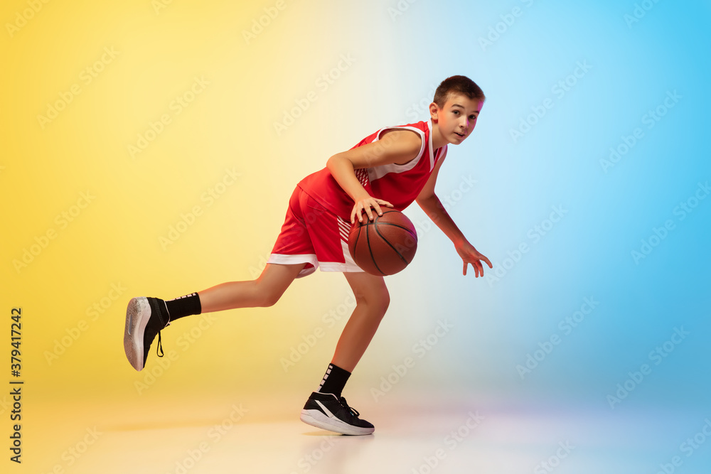 Hurry up. Portrait of young basketball player in uniform on gradient studio background. Teenager confident practicing with ball. Concept of sport, movement, healthy lifestyle, ad, action, motion. Hurry up. Portrait of young basketball player in uniform on gradient studio background. Teenager confident practicing with ball. Concept of sport, movement, healthy lifestyle, ad, action, motion.