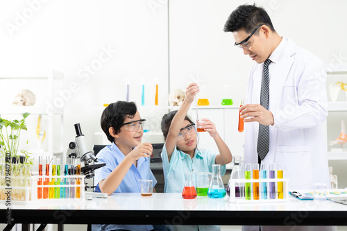 child students doing or testing a chemical experiment with science teacher in laboratory classroom