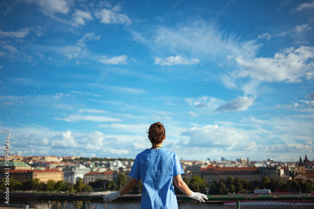 modern physician woman in scrubs outdoors in city against sky modern physician woman in scrubs outdoors in city against sky