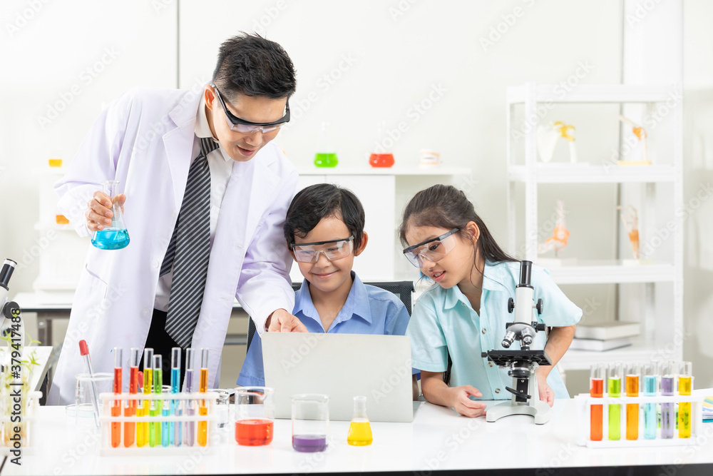 science teacher and child students using computer laptop for finding information about science science teacher and child students using computer laptop for finding information about science