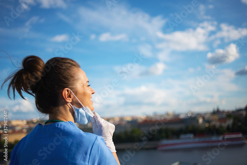 smiling modern physician woman breathing outside against sky