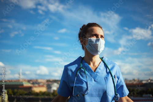 modern medical doctor woman in uniform outside against sky