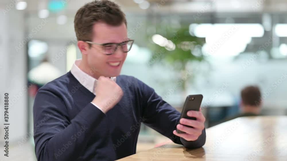 Young Businessman Celebrating Success on Smartphone Young Businessman Celebrating Success on Smartphone