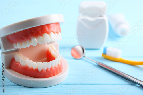 model of teeth and dental instruments and dental care products on colored background