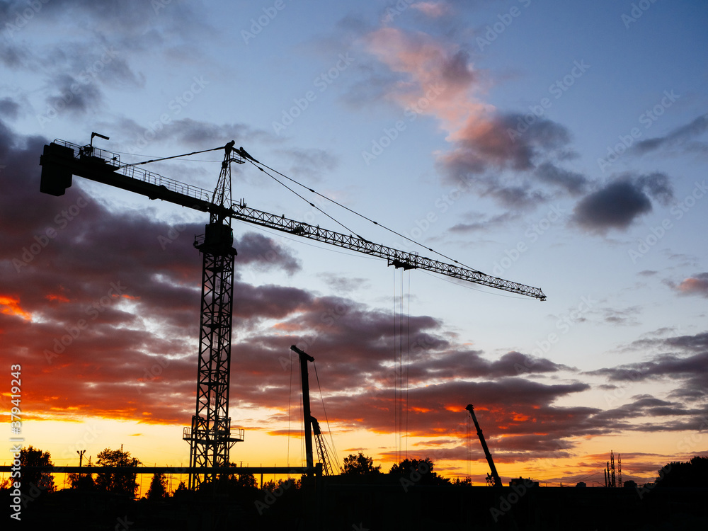 Construction crane on the background of a beautiful bright sky. Concept of new housing construction. Shared construction. Industrial urban construction scenic background or screen saver