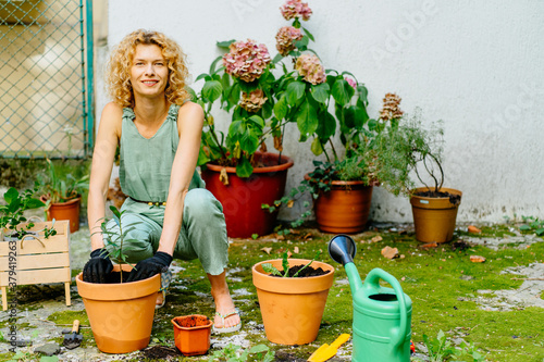 Middle age graceful woman replaning plant it bigger pot in backyard garden. Hobbie, leisure, relaxing after work concept. Change of activity the best rest.
