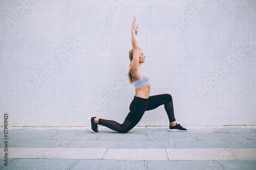 Sportive female doing stretching on asphalt