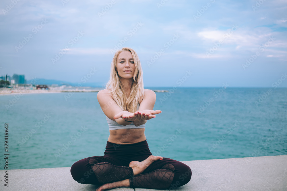 Young woman doing yoga on seafront