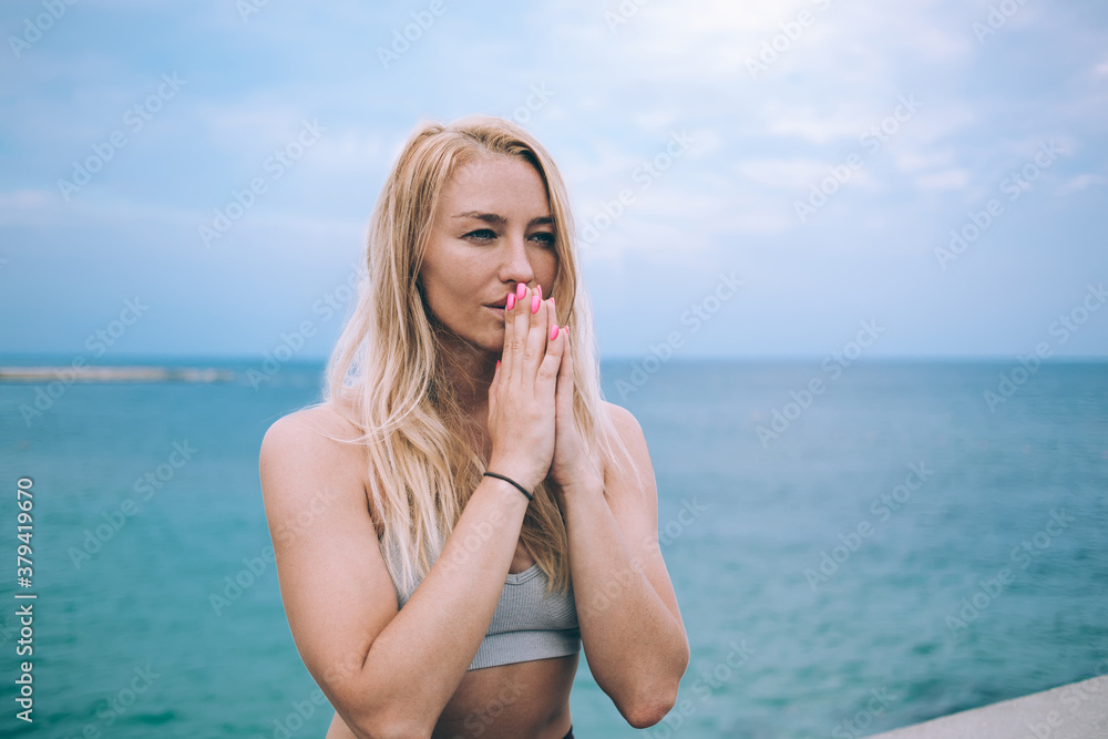 Caucasian woman calms brain minds with time for pray enjoying morning enlightenment near coastline, good looking female yogi increases awareness and attentiveness with padmasana meditation exercise