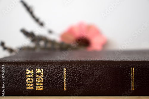 Closed Christian Holy Bible Book with golden letters. Flower background. Read and pray to God Jesus Christ. Morning prayer. A close up. photo