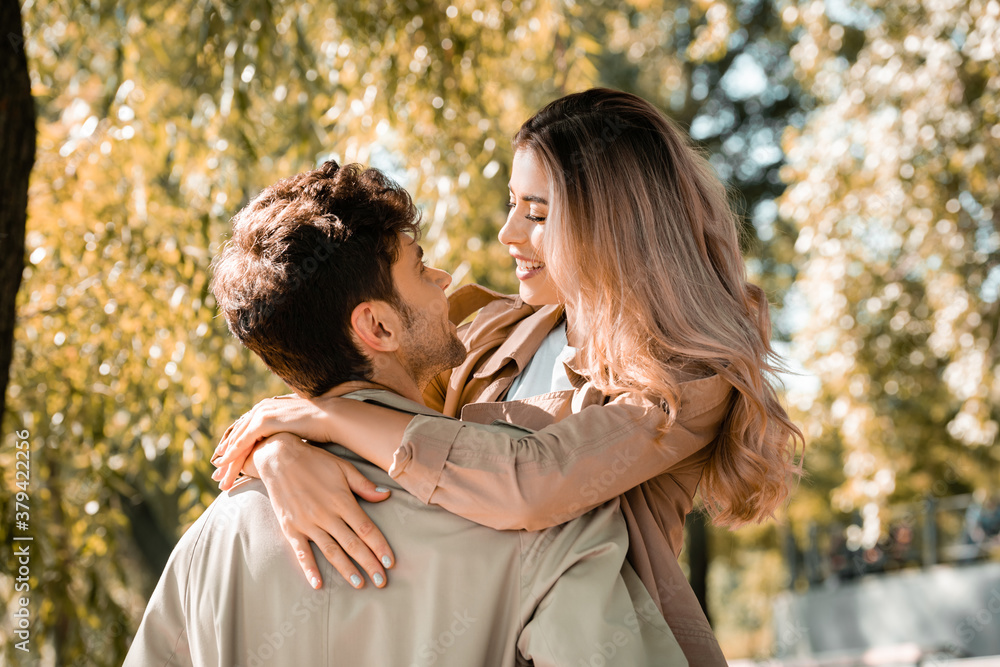 woman hugging and looking at boyfriend in autumnal park woman hugging and looking at boyfriend in autumnal park