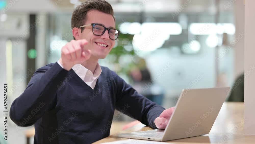 Young Businessman with Laptop Pointing at the Camera Young Businessman with Laptop Pointing at the Camera