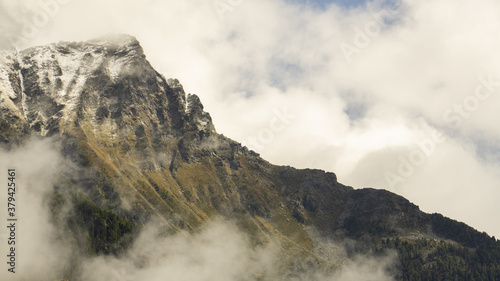 View of Corno Bussola (Valle d'Ayas, AO) surrounded by clouds and covered by snow after a storm in august. 