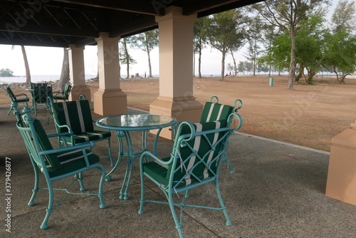 A set of an empty green chair and table by the beach for hangout or discussion during leisure time