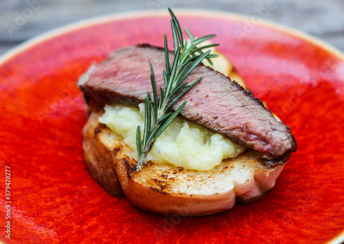 Grilled beef cooked medium-rare on creamy mash crostini. photo