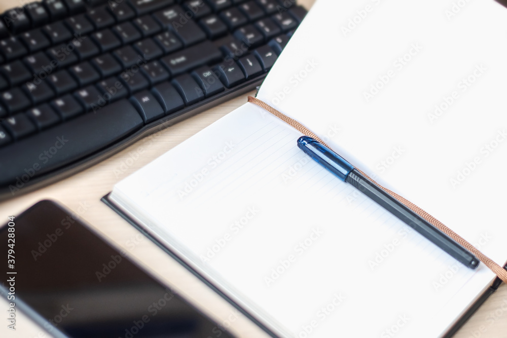 Desktop scene with keyboard, mobile phone and notebook for planning and leaving notes. Business management and organization of tasks at work. Studying or freelancing using notepad organizer and cell Desktop scene with keyboard, mobile phone and notebook for planning and leaving notes. Business management and organization of tasks at work. Studying or freelancing using notepad organizer and cell