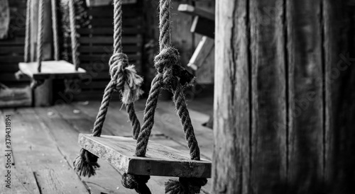 Wooden swing tied with rope in monotone , lonely mood concept and no people. Copy space for text on right. selective focus on swing.