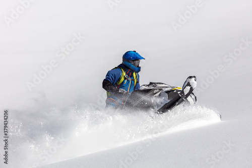 professional snowmobiler makes a turn on a large snow-white field. sports snowmobile in the mountains. bright skidoo motorbike and suit without brands. Winter fun moto extreme. Copy space