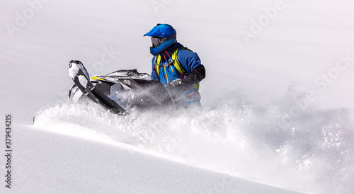 professional snowmobiler makes a turn on a large snow-white field. sports snowmobile in the mountains. bright skidoo motorbike and suit without brands. Winter fun moto extreme. Copy space