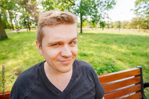 Portrait of a young man on nature background. Emotion facial expression. © mdyn