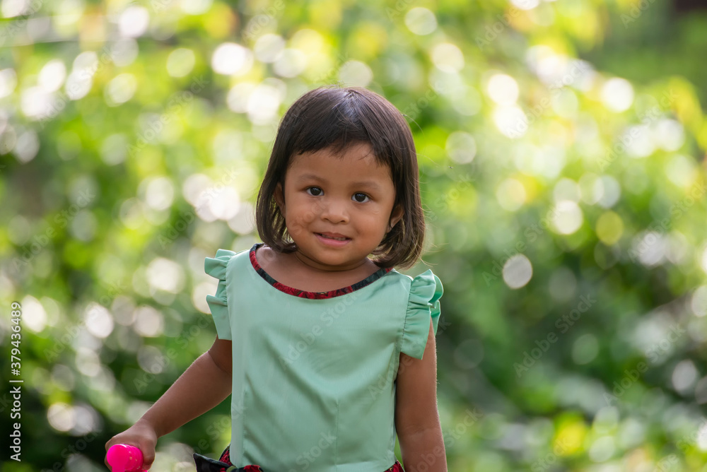 Asian child laughing and smile with white teeth in nature background. Close up Headshot Thai kid Happy fun in park