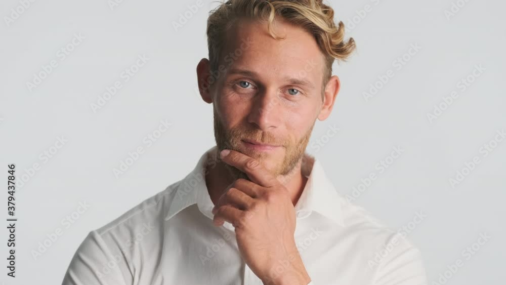 Attractive blond bearded man thoughtfully looking in camera and smiling over white background Attractive blond bearded man thoughtfully looking in camera and smiling over white background