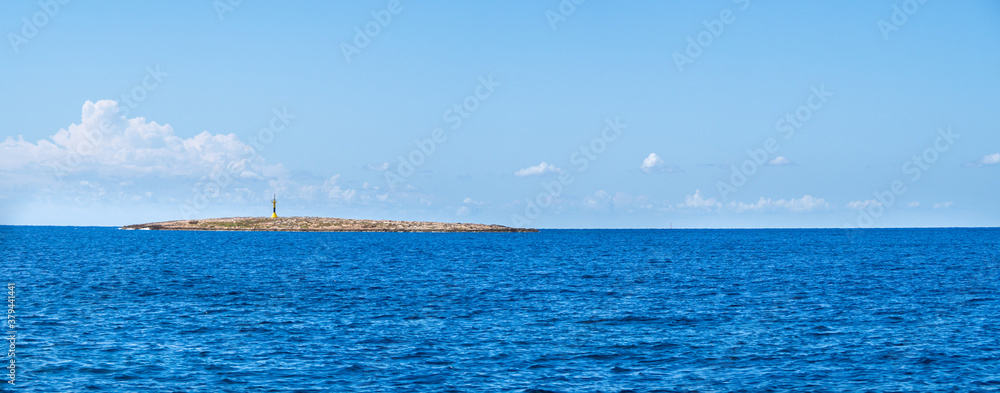 Panoramic view of a small rocky island with lighthouse in the mediterranean sea.