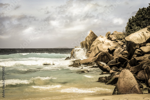 August cloudy day on a warm Seychelles' sandy beach with huge boulders.