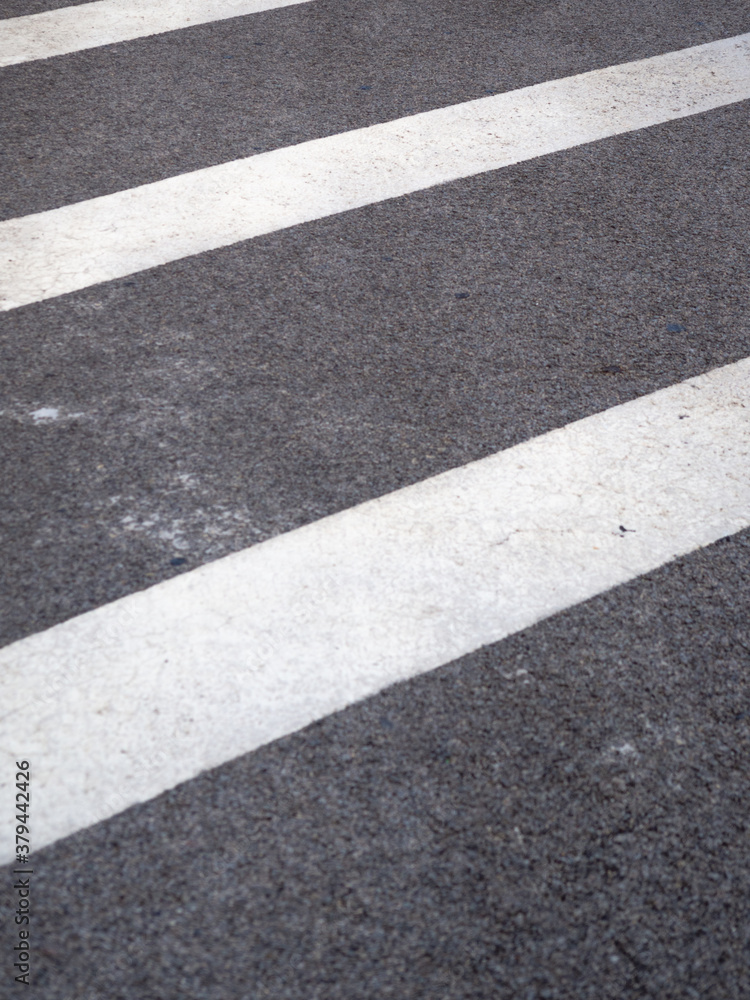 Closeup of a tar or asphalt pavement texture with white lines painted on asphalt road