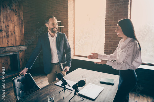 Profile photo of two people businessman business lady partnership colleagues press conference secretary offer sit down famous professor reportage microphone table office indoors