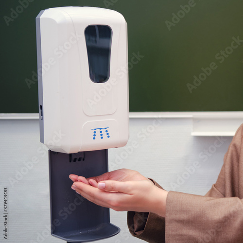 Student disinfects her hands in a dispenser with a sanitizer