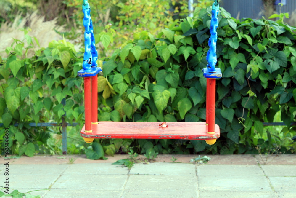an empty children's swing set against a winding green fence an empty children's swing set against a winding green fence