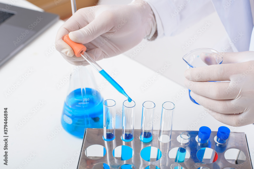 Fototapeta premium close up of cientist is testing and researching some blue liquid chemical in laboratory isolated white background.