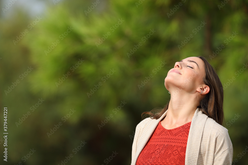 Relaxed woman breathing standing in a park a sunny day Relaxed woman breathing standing in a park a sunny day