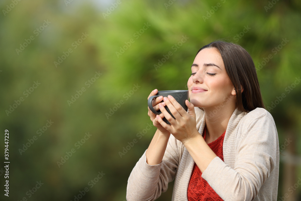 Relaxed woman holding coffee cup breathing fresh air