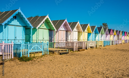 Obraz na płótnie A view along brightly coloured beach huts on West Mersea beach, UK in the summer