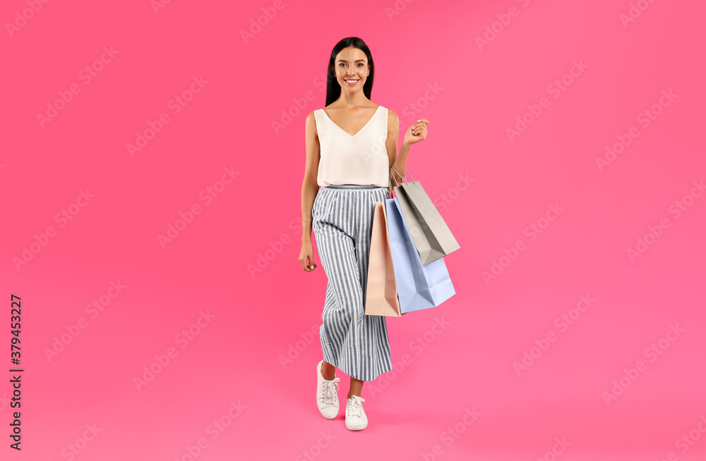 Beautiful young woman with paper shopping bags on pink background Beautiful young woman with paper shopping bags on pink background