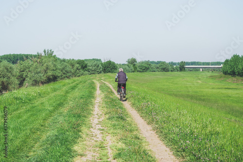 senior man riding bicycle on rural road