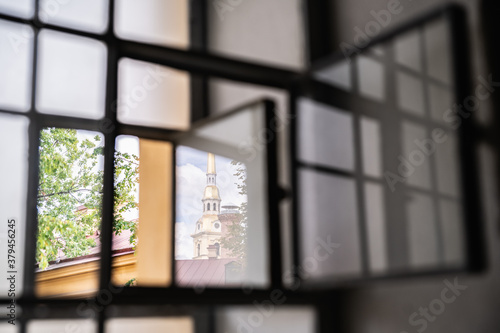 The spire of the Peter and Paul Cathedral through the reflection in the glass of the Trubetskoy bastion window overlooking the courtyard for prisoners