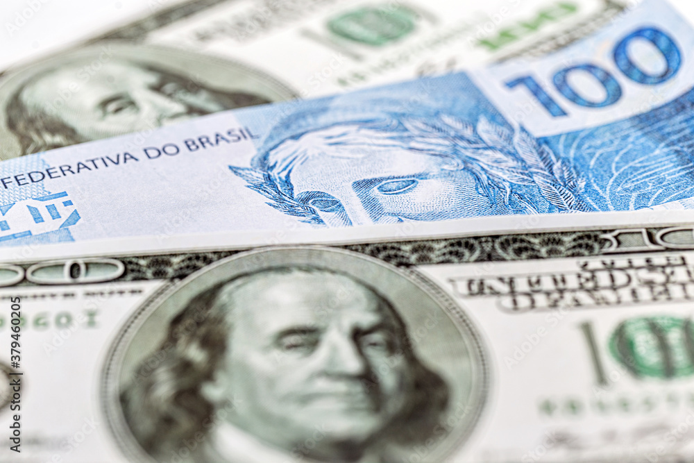 one hundred Brazilian banknotes and one hundred American dollars banknotes, concept of Brazilian economy in crisis, devaluation of the Brazilian real. one hundred Brazilian banknotes and one hundred American dollars banknotes, concept of Brazilian economy in crisis, devaluation of the Brazilian real.