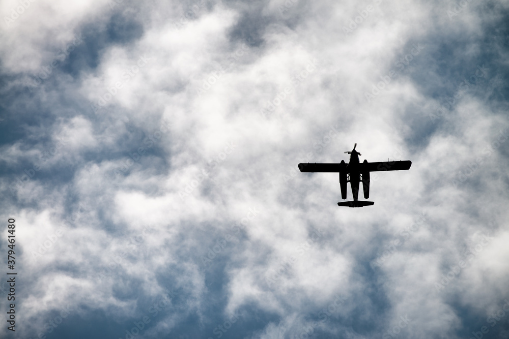 Biplane flying in the cloudy sky. Retro style, airplane silhouette, upward view Biplane flying in the cloudy sky. Retro style, airplane silhouette, upward view