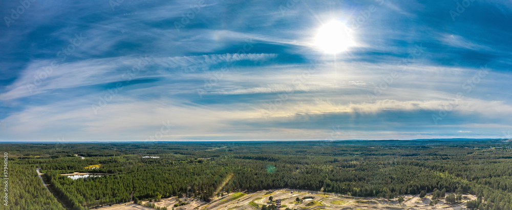 Breathtaking Aerial View of Endless Scandinavian green pine tree forest up to horizon line, part of speedway training track below. Sunny summer day. Typical Northern Scandinavia landscape