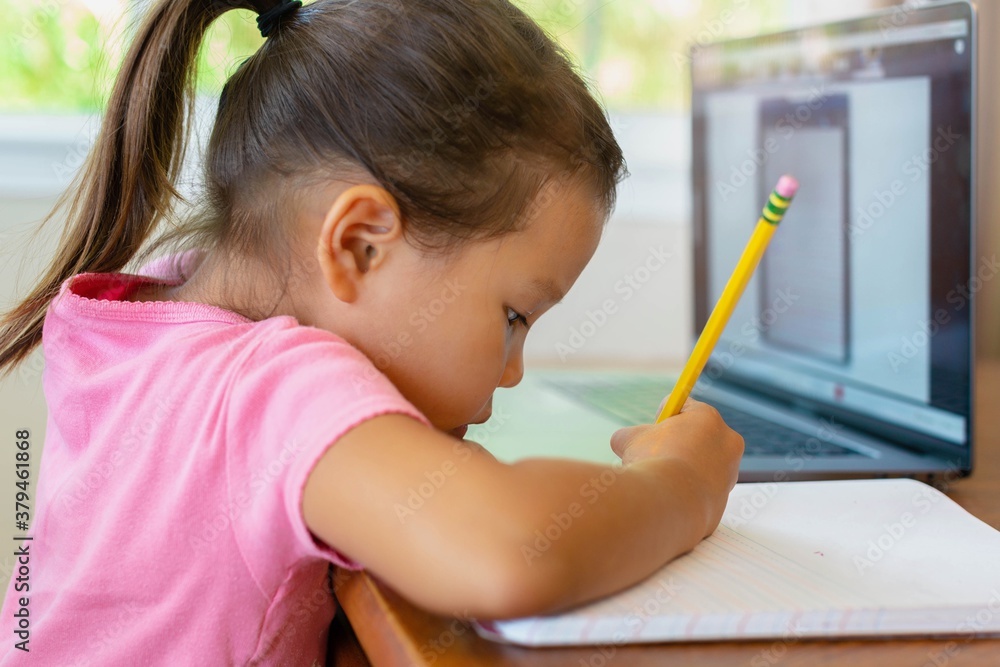 A kindergarten student learning how to write with pencil and paper, online school. Distance learning. A kindergarten student learning how to write with pencil and paper, online school. Distance learning.