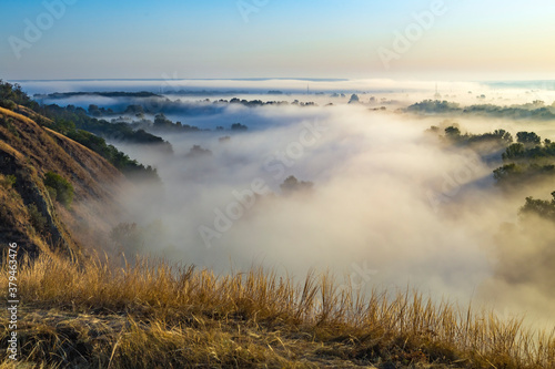 Fototapeta Naklejka Na Ścianę i Meble -  Beautiful panoramic landscape with river valley covered by thick fog in autumn in the early morning. Sunrise.