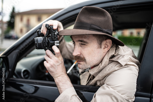 Paparazzo photographer, detective using camera in his car
