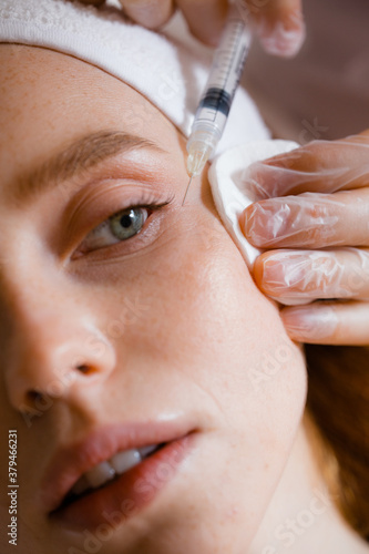 Portrait of a girl at the beautician's procedure. Close-up of a cosmetologist who makes injections to get rid of facial wrinkles